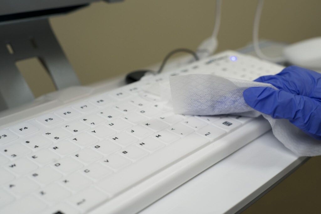 Gloved hands cleaning a white Seal Shield low profile keyboard
