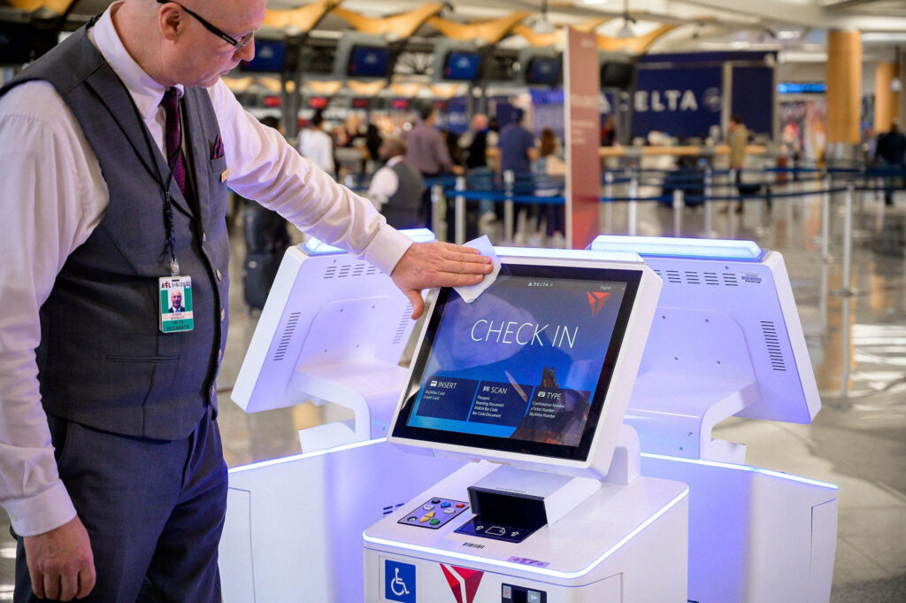 Airport employee is cleaning one of the kiosk screens