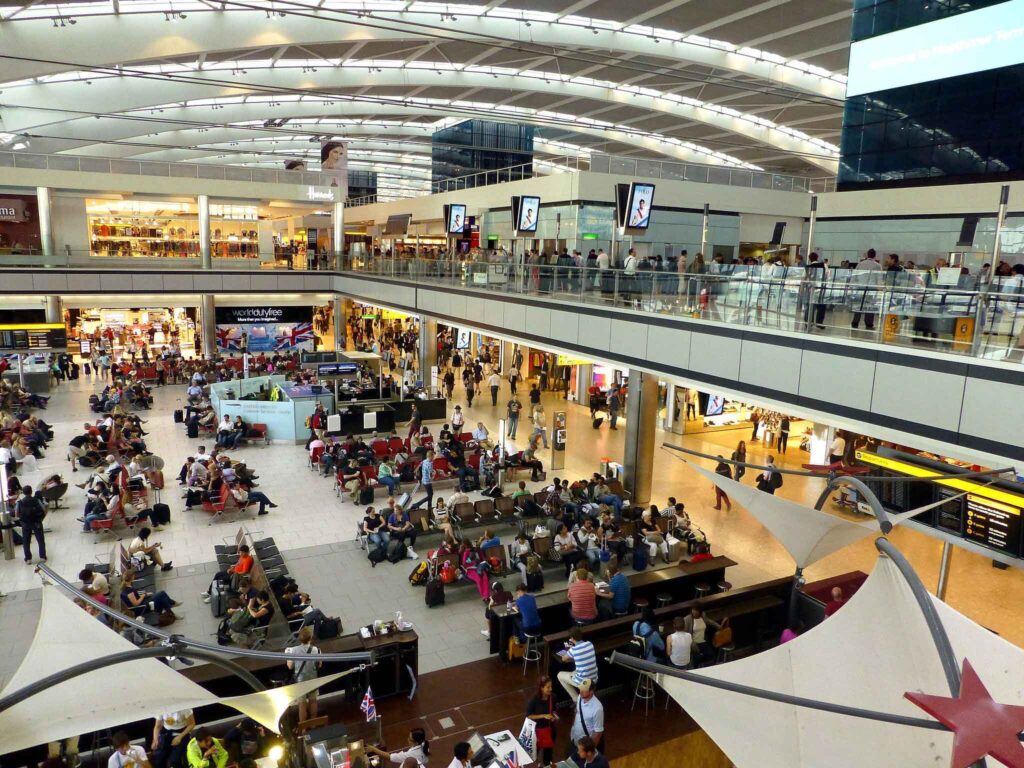 Airport terminal packed with travelers experiencing delays and some are reading what's on their phone screens
