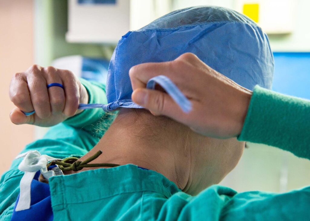 A nurse wearing a gown and head covering for infection control